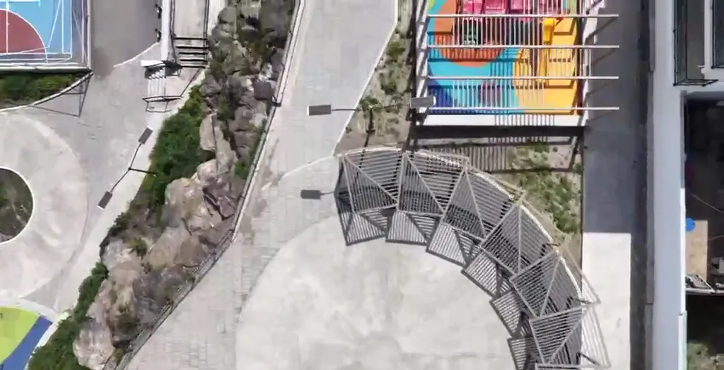 Vista aérea a plomo de un parque deportivo con cancha de colores, skatepark y andadores