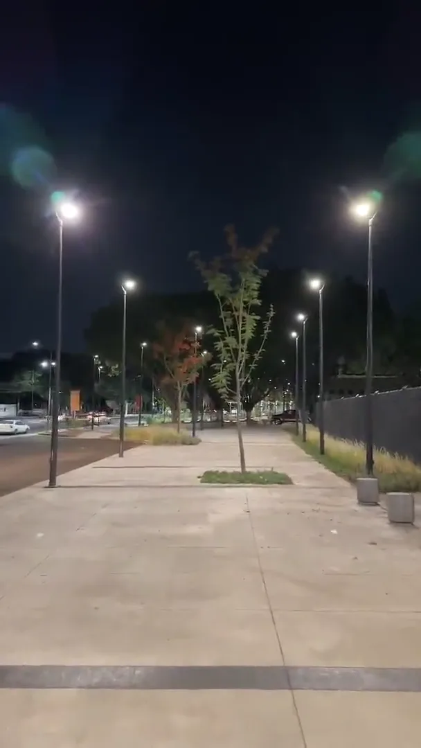 Andador peatonal y estacionamiento iluminados de noche con postes LED en hilera
